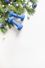 Sport Christmas frame with blue dumbbells, holiday baubles on white. Greeting card for fitness club.