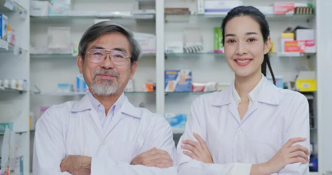 Two Pharmacist posing at pharmacy shop with smiling. Friendly happy physician posing and looking at camera in drugstore.
