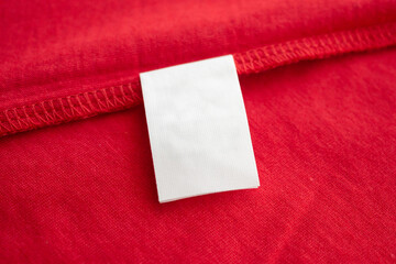 White laundry care washing instructions clothes label on red cotton shirt