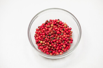 Red peppercorns in glass bowl isolated on white background, organic hot species, dried pepper corns balls, indian natural spice. Food concept, chili pepper grains cosmetic ingredients. Text space