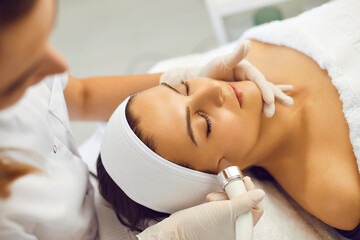 Obraz na płótnie Canvas Hands of cosmetologist making facial regeneration treatment for woman in spa salon