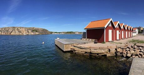 Fototapeta na wymiar A groupe of typical swedish red houses on the beach of the fjord
