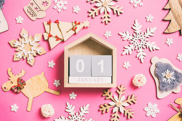 Top view of calendar on pink background made of holiday decorations and toys. Christmas ornament concept