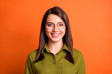 Photo portrait of smiling cheerful female worker wearing glasses isolated on bright orange color...