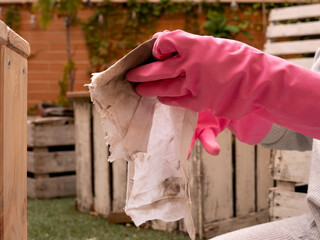 RESOURCES OF WOMAN'S HAND GIVING WAX TO WOODEN BENCH WITH PINK RUBBER GLOVES