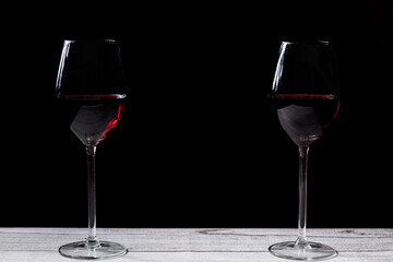 Dos copas de vino negro con tabla gris y fondo negro