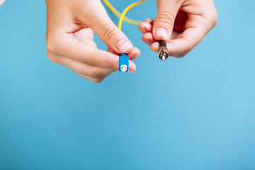 woman's hands hold SC and FC connector fiber optic patch cord single mode on blue background