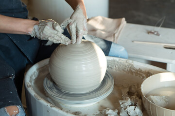 potter works pottery wheel. woman make ceramic vase by hand from wet clay