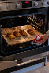 Woman baking fried fish in hot oven in the kitchen as delicious meal for the family as healthy nutrition and a yummy lunch and dinner preparation on baking paper with high temperature and fire danger