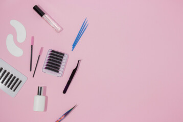 Things for the work of lash-makers, artificial eyelashes, microbrachis, glue, tweezers, combs, brushes. Eyelash extension, painting of eyebrows. Top view, pink background, free space for text.