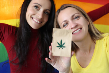 Two women are holding a lgbt flag and paper bag with marijuana sign. How marijuana affects sexual...