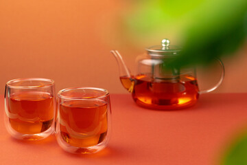 Glass teapot and two glass cups with tea