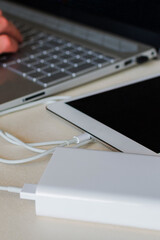 Power bank charges tablet on desk. Universal external batter