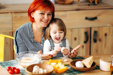Cook together at home. Red-haired grandmother and little granddaughter cook pizza in a cozy home. Have fun in the kitchen