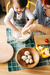 Cook together at home. Red-haired grandmother and little granddaughter cook pizza in a cozy home. Have fun in the kitchen