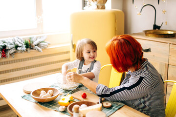 Cook together at home. Red-haired grandmother and little granddaughter cook pizza in a cozy home. Have fun in the kitchen