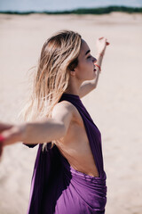 Young, slender girl with purple cloth poses in the desert