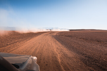 Off road 4x4 vehicle in dry mountainous desert area leaving dust trail © Liam M
