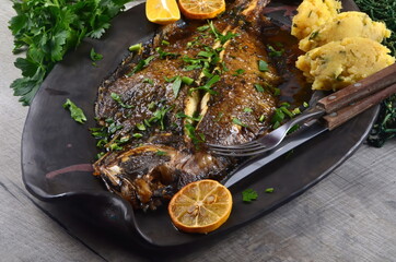 Two whole fresh flounder, butter, and lemon on black baking sheet  Sole Meuniere recipe