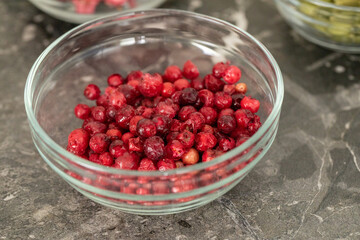 Freeze-dried organic cranberry berries in glass bowl for decorating cakes, pastries and handmade chocolates. Useful filling for porridge, muesli, yogurt, sauce, dressing. Pastry, natural food concept