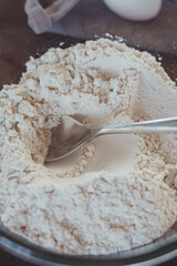 Dough preparation process, flour in a large glass bowl close-up.
