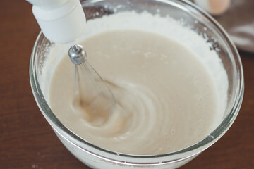 Process of kneading the dough with a mixer in a large glass bowl.