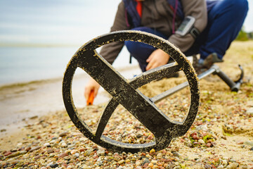 Man with metal detector on sea beach