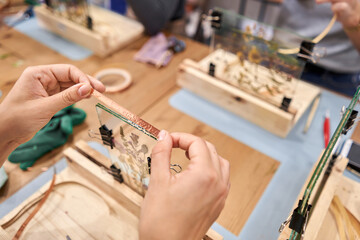 A woman glues metal tape for soldering with a soldering iron. Master class on creating frame with...