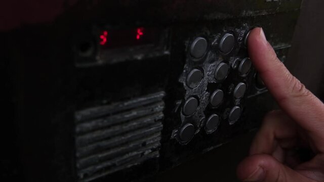 human finger presses the intercom button, a man opens the door by entering the code on the old intercom