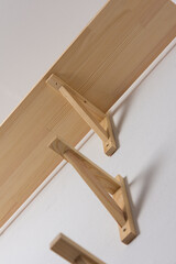 The process of attaching a wooden shelf to the wall, shelf corners together with a bookshelf