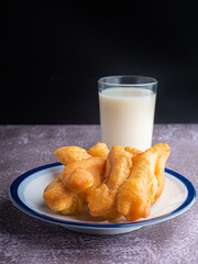 Close-up of deep-fried dough sticks or Chinese doughnut sticks on a white plate and a glass of...