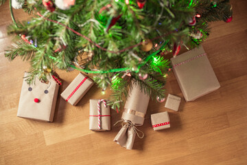 Hand made gift wrapping in a kraft paper under christmas tree. Presents for family. Top view. Flat lay.