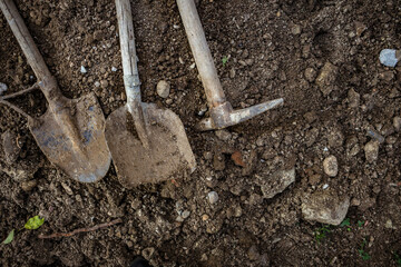 Dirty shovel, pickaxe and spade lying on the ground. Tools for seasonal garden work and for digging at construction site.