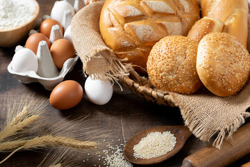 Wheat round bread. Wheat bread is surrounded by baking ingredients. Bread close-up. Eggs, salt, flour, seeds on the kitchen table