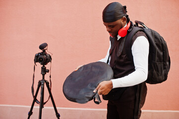 Young professional african american videographer holding professional camera with pro equipment. Afro cameraman wearing black duraq making a videos.