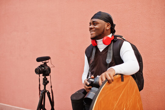 Young professional african american videographer holding professional camera with pro equipment. Afro cameraman wearing black duraq making a videos.