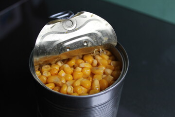yellow sugar corn in a tin metal can on a dark background of copy space