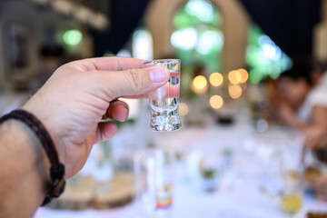 Wedding or party concept. Hand with a glass of vodka guest makes a toast, raising a glass