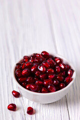 Pomegranate in white bowl on wooden table