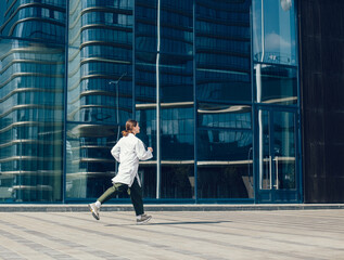 concerned woman doctor running near a city building.