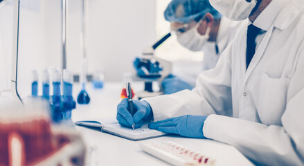 close up. scientist recording the results of the study in a laboratory journal.