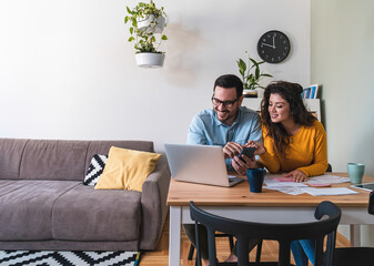 Smiling husband and wife paying bills online