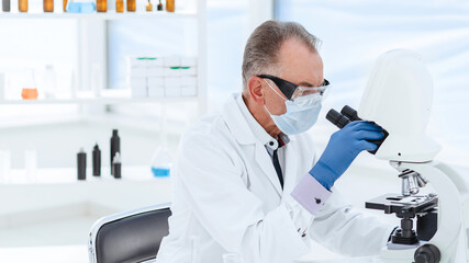 scientist in a protective mask conducts research in the laboratory.