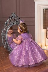 Little princess with a smile looking at herself in the mirror. Fairy tale. 