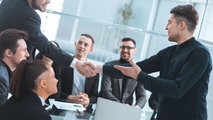 smiling business people shaking hands over an office Desk