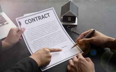 Agreeing to buy a house, a man's hand is about to sign an agreement or a contract for buying a home that he has spoken to with the real estate agent.