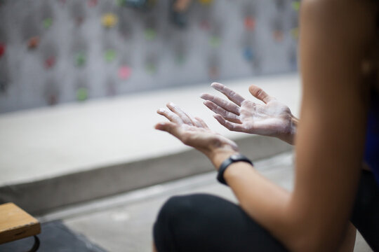Climber woman using liquid chalk magnesium preparing to climb indoor, close-up