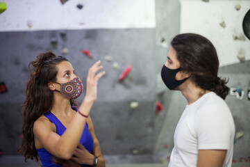 Climbing wall instructor and student wearing mask on steep rock wall indoors