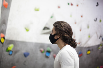 young fit male climber wearing mask on steep rock indoors