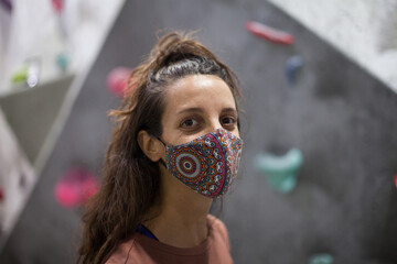 young fit woman climber wearing mask on steep rock indoors